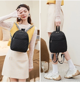 Macro detail of black quilted mini backpack featuring V-pattern stitching and letter print straps