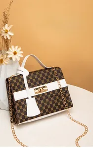 Detail of printed crossbody bag with golden twist lock and elegant floral pattern