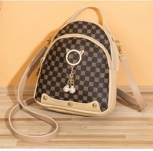Détail du mini sac à dos marron avec motif trèfle doré et pendentif chat en perle