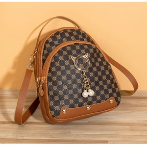 Détail d'un mini sac à dos à motif trèfle avec breloque chat dorée et perles