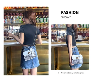 Chic women's crossbody bag with snakeskin pattern and golden lock detail in lifestyle setting