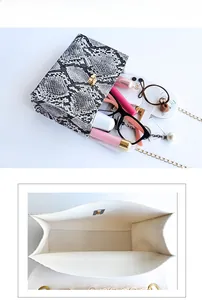 Detail of snake print crossbody bag showing spacious interior with phone and lipstick