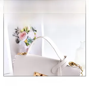 Detail of white lychee leather texture with gold metal twist lock and durable top handle