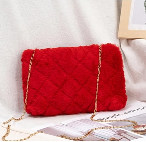 Macro detail of red faux fur crossbody bag featuring quilted patterns and gold chain strap