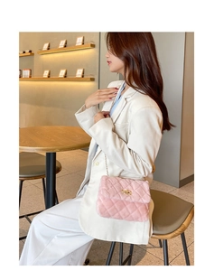 Pink plush quilted crossbody bag with gold chain strap shown on a model in a cafe