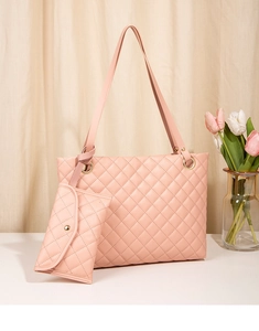 Detailed view of pink quilted tote bag with matching envelope pouch on a white surface