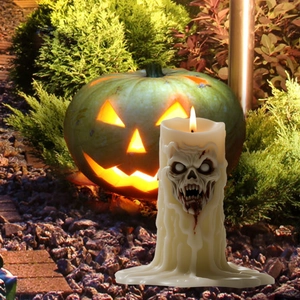 Spooky white Halloween skull candle with dripping blood effect in a garden setting