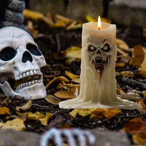 Creepy Halloween skull candle with melting wax texture on autumn leaves outdoor background
