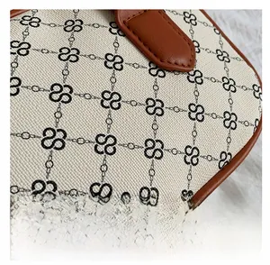 Close-up of canvas texture with floral chain print and brown leather stitching details