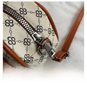 Detail of the smooth silver metal zipper and brown leather trim on the canvas Boston bag