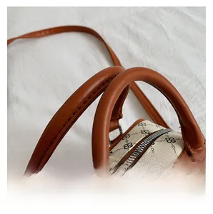 Close-up of printed canvas Boston bag featuring brown leather handles and silver hardware