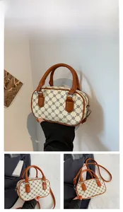 Detail of beige Boston bag with vintage monogram pattern and brown handles in hand