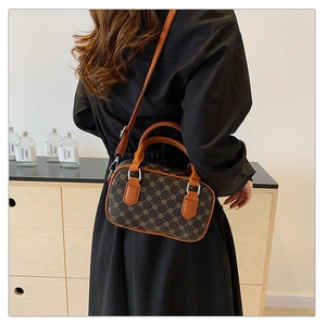 Detail of retro mini barrel bag with clover pattern and orange-brown straps on model