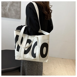 Close-up of large white tote bag with black HODO lettering on wide shoulder strap