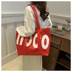 Detailed side view of large red canvas tote bag with white moco print and long handle