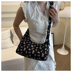 Close-up of black crescent bag with white bow print and comfortable wide shoulder strap