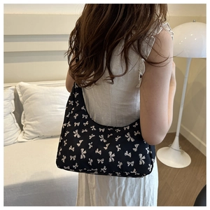 Floral hobo shoulder bag with white bow print patterns shown on a model in a warm room