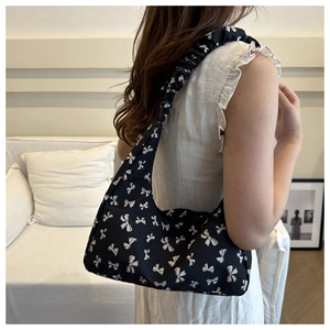 Detail of black shoulder bag with white bow patterns and stylish ruched strap detail