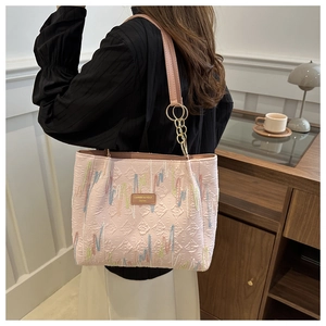 Détail du sac cabas plissé rose clair avec broderie multicolore et bandoulière en chaîne