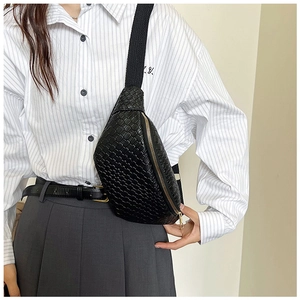 Détail du sac de poitrine en cuir tressé noir avec fermeture éclair dorée et sangle