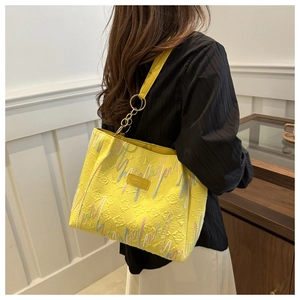 Detalle del bolso tote amarillo plisado con ondas de colores y anillas doradas