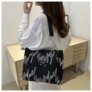Detail of black tote bag featuring colorful wave embroidery and gold chain shoulder strap
