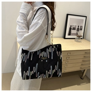 Détail du sac cabas noir avec broderie vagues colorées et bandoulière chaîne dorée