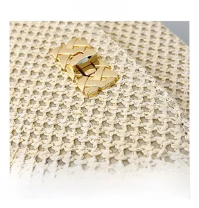 Detail showing the textured beige straw weaving and polished gold metal clasp lock