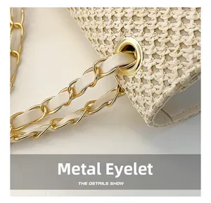 Detail of woven straw handbag featuring gold chain strap and metal eyelet accents