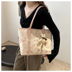Detail of a large tote bag with pink graffiti print and a cute teddy bear charm accessory