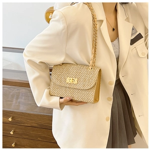 Detail of woven straw bag with golden twist lock and elegant leather chain strap