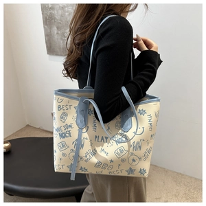 Detail of a large cream PU tote bag featuring vibrant sky blue graffiti and shoulder straps