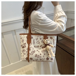 Dettaglio borsa tote in pelle PU con stampa graffiti, ciondolo orsetto e manici marroni