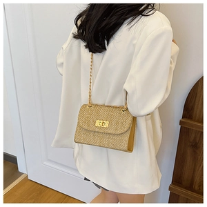 Detail of woven straw shoulder bag featuring gold chain strap and metallic twist lock clasp