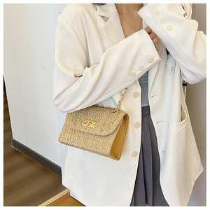 Detail of straw woven square bag with gold chain strap and metallic twist lock clasp
