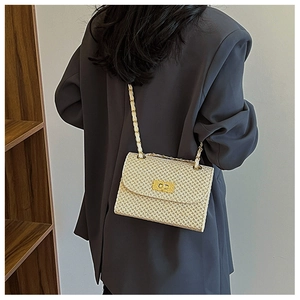 Close-up of woven crossbody bag featuring textured honeycomb pattern and gold metal clasp