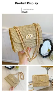 Detailed view of khaki straw woven handbag featuring a gold turn-lock and chain strap
