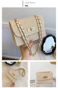 Detail of cream straw woven bag featuring a gold twist lock and chain shoulder strap