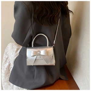 Détail du sac à main argenté métallisé avec grand nœud et poignée élégante