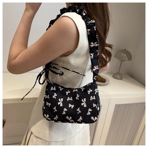 Detail of canvas shoulder bag featuring white bow patterns and ruched scrunchie strap