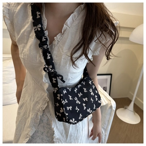 Detail of black bow-print shoulder bag with pleated strap and sweet vintage style