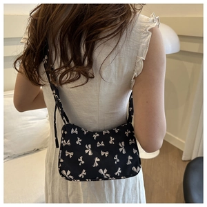 Close-up of black floral shoulder bag with white bow prints on high-density fabric