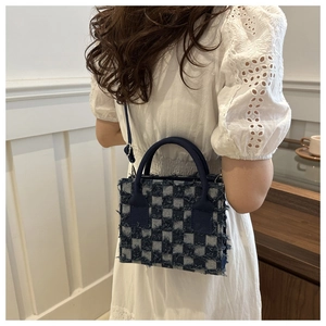 Detail der karierten Denim-Umhängetasche mit Fransenrändern an der kleinen quadratischen Tasche