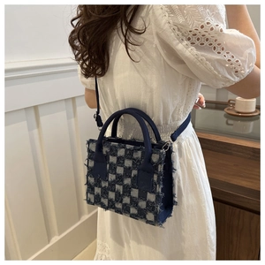 Detail der kleinen blau-grauen karierten Denim-Tote-Bag mit Fransen und Umhängeriemen