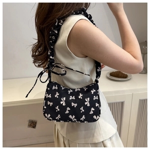 Detail view of the floral bow print fabric and ruched shoulder strap of this hobo bag