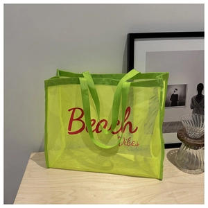 Detailed macro view of neon mesh tote bag with Beach Vibes red print and woven handle