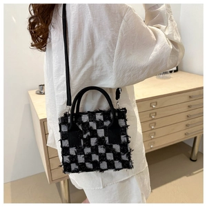 Detailansicht der schwarz-grau karierten Tweed-Handtasche mit Fransen und Ledergriff