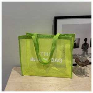 Detail of neon green mesh beach bag featuring THE BEACH BAG white artistic typography