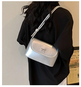 Detail showing the silver metallic shoulder bag with decorative bow and knot on strap