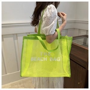 Detailed view of large capacity bright green mesh beach tote bag with white text